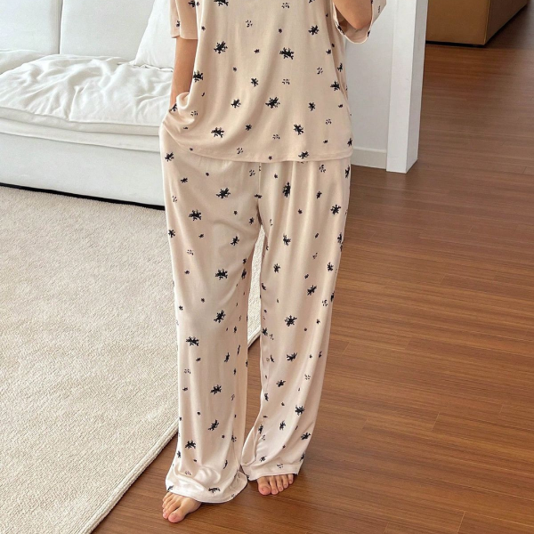Person wearing a beige pajama set with black patterns in a living room.